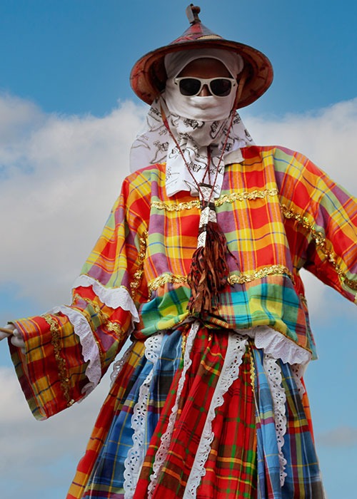 moko-jumbie Moko Jumbie in colorful madras with blue sky background
